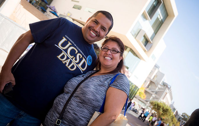 Parents of new UC San Diego student wearing UCSD shirts and smiling.