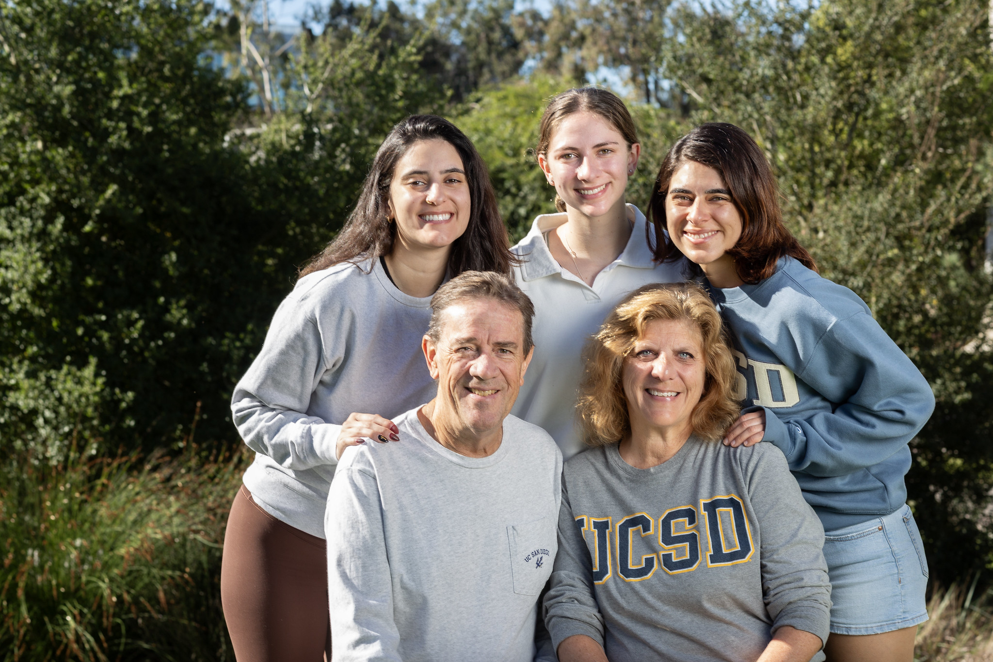 Smiling family in UC San Diego shirts during family weekend. 